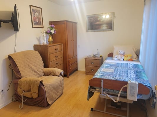 A comfortable bedroom with a bed, armchair, and dresser.