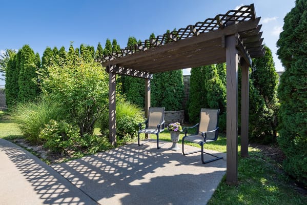 Two chairs under a wooden pergola in a garden