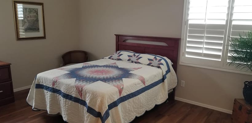 Cozy private bedroom with quilt and shutters