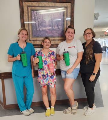 Four staff members holding drinks in a hallway.
