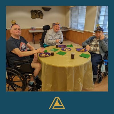Three senior men with game hats share snacks at a table.