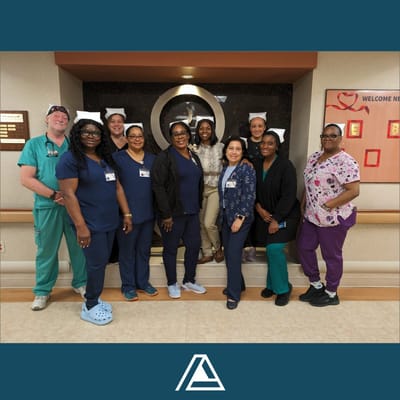 Group photo of Atlas Healthcare staff in front of the facility's logo