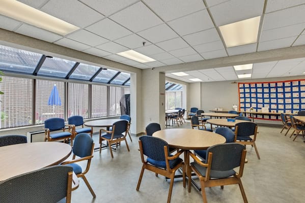 Common area with tables and chairs, large windows, and an inviting atmosphere.