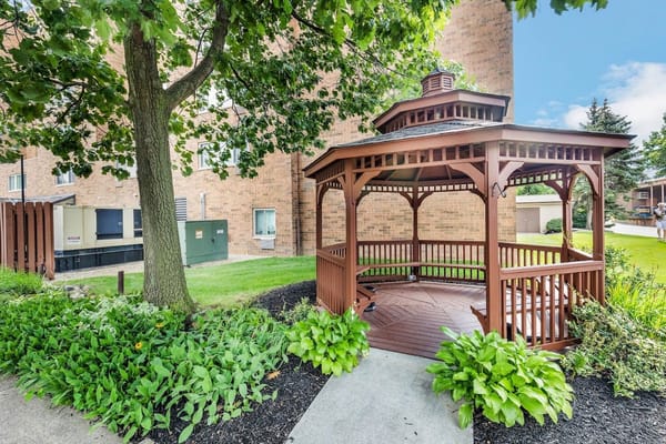 Wooden gazebo surrounded by greenery at Campbell Court Senior Apartments