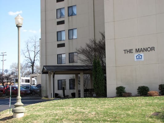 The Manor building with a covered entrance and lamp post