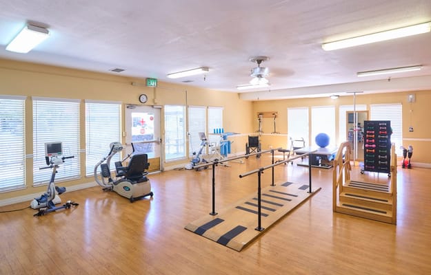 View of therapy gym with exercise equipment and therapy bars