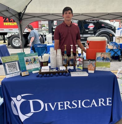 A staff member at an outdoor event table promoting Diversicare