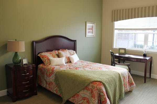 Well-decorated private resident room with a bed and desk