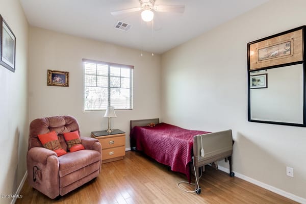 A cozy bedroom with a bed, recliner, and bedside table.