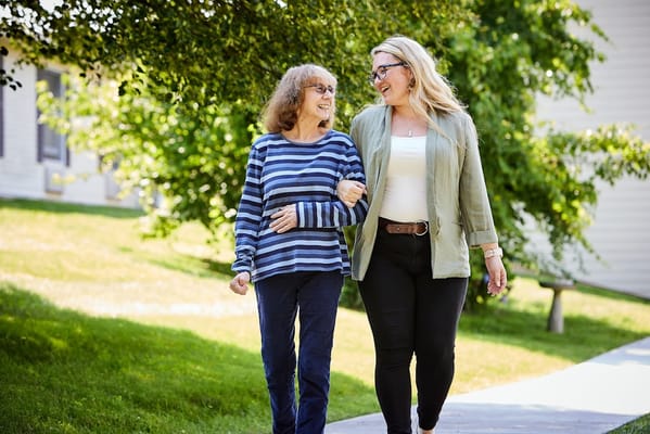 Two women walking outdoors in a sunny environment