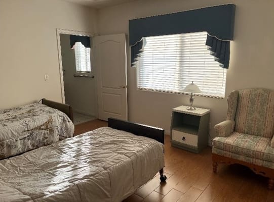 Bedroom with two beds, a lamp, and a chair