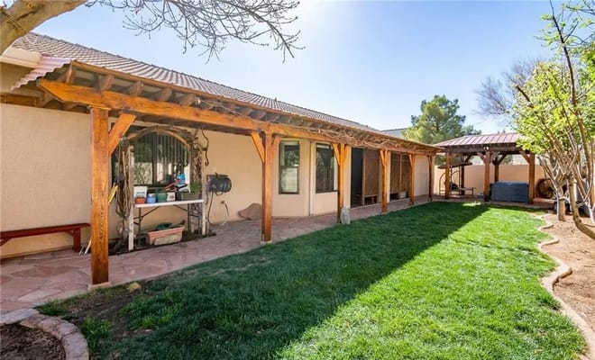 Outdoor patio area with grass and wooden structure