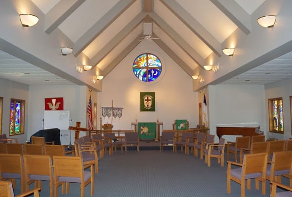 Interior view of a chapel with wooden chairs and stained glass windows