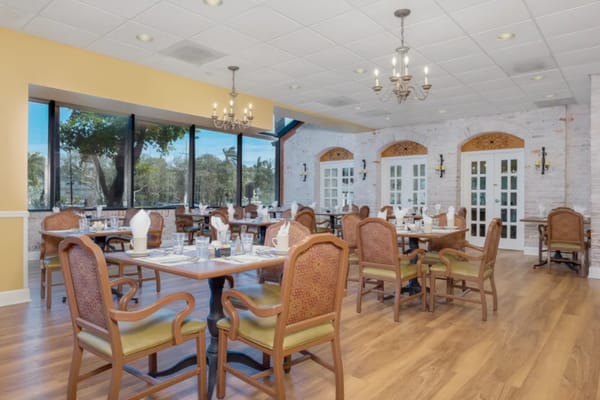 Well-arranged dining room with tables and chairs, large windows, and chandelier lighting
