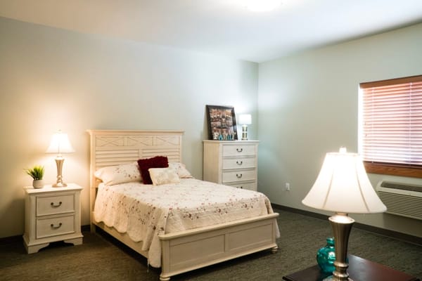 Well-furnished private resident room with a bed and dresser