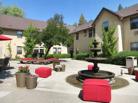 Courtyard featuring a fountain and red seating at Hilltop Commons Senior Living