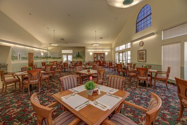Spacious dining room with wooden tables and chairs, decorated with plants.