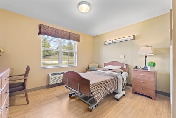 A well-furnished resident room with a bed and chair