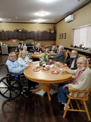 Seniors gathered around a table with snacks and drinks.