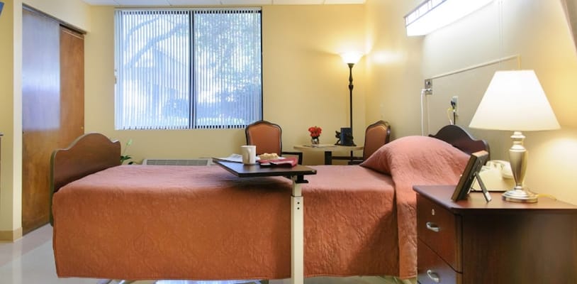 A cozy private resident room with a bed and lamp
