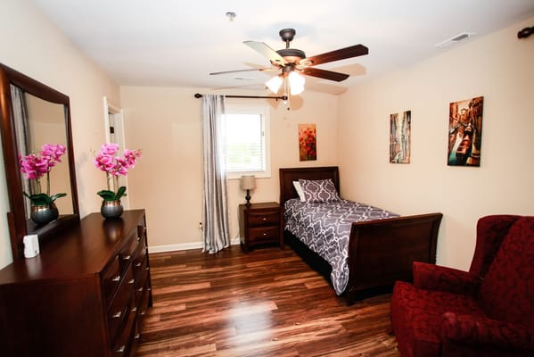 A well-furnished bedroom with a bed, dresser, and decorated walls.