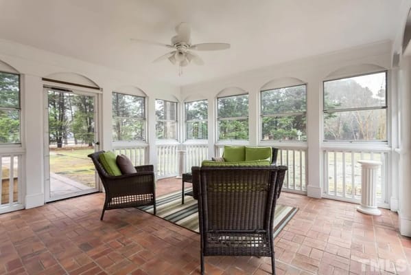 Cozy sunroom with wicker chairs and a view of greenery.