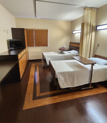 A shared bedroom with two beds, a TV unit, and natural light from a window.