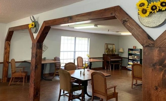 Bright common area with tables and chairs surrounded by wooden arches.