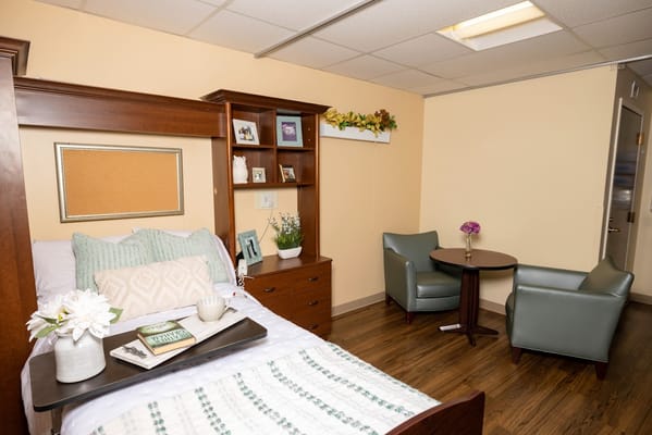 A well-decorated bedroom with a bed, bookcase, and seating area.