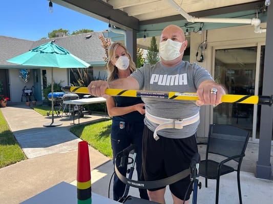 A therapist assists a resident with a balance exercise outside