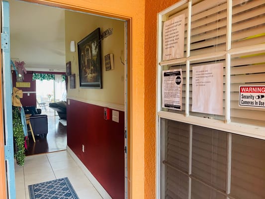 View from the entrance with security notices and a living area visible through the doorway.