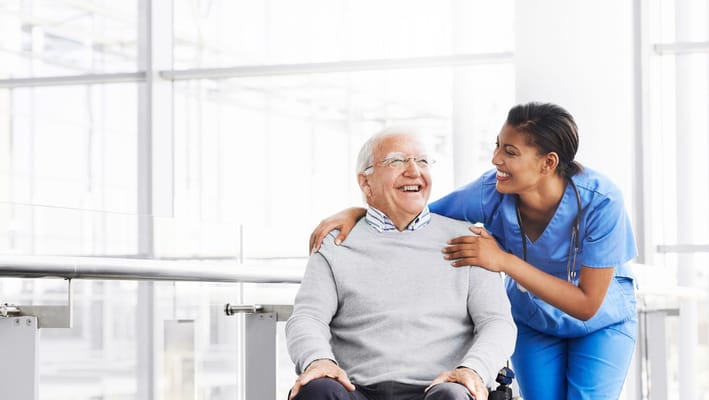 A senior man smiling with a caregiver in a bright facility