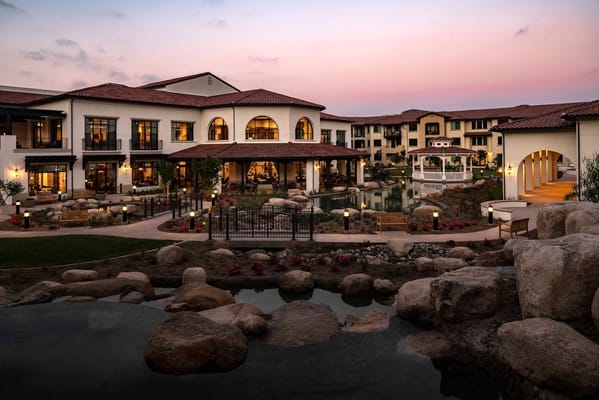 Exterior view of Reata Glen senior living facility with landscaped garden and soft sunset lighting.