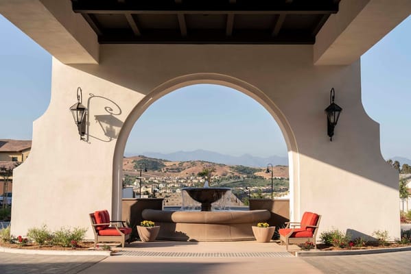 A view of the entrance with a fountain and seating area under an arch.