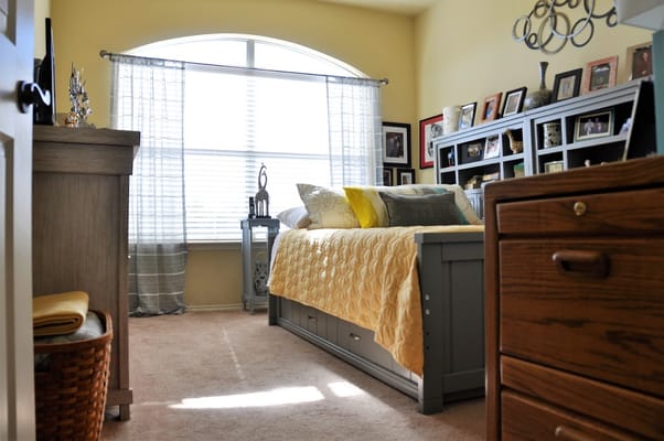 Bright and inviting senior bedroom with a quilted bedspread and personal decorations
