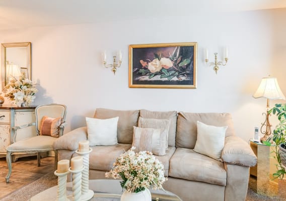 A cozy living room with a beige couch, decorative pillows, and floral arrangements