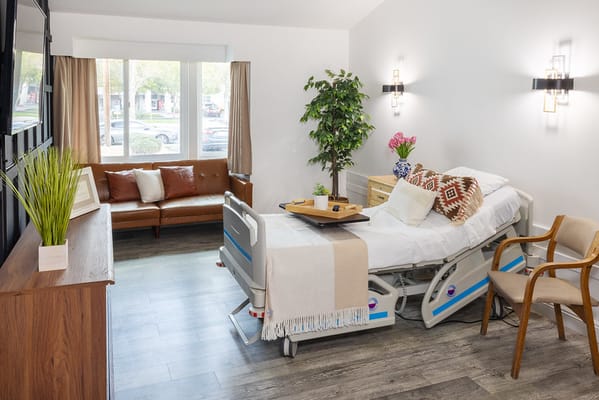 Bright and inviting nursing bedroom with bed, couch, and plants.