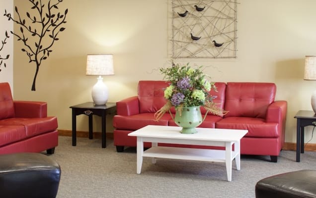 Living room with red sofas and floral arrangement.