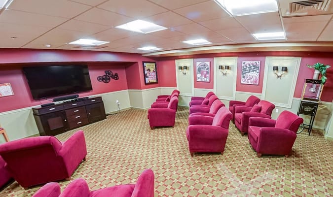 Lounge with red chairs and a television in Stafford Hill Assisted Living