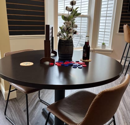 A round table with game pieces, a floral arrangement, and a beverage bottle.