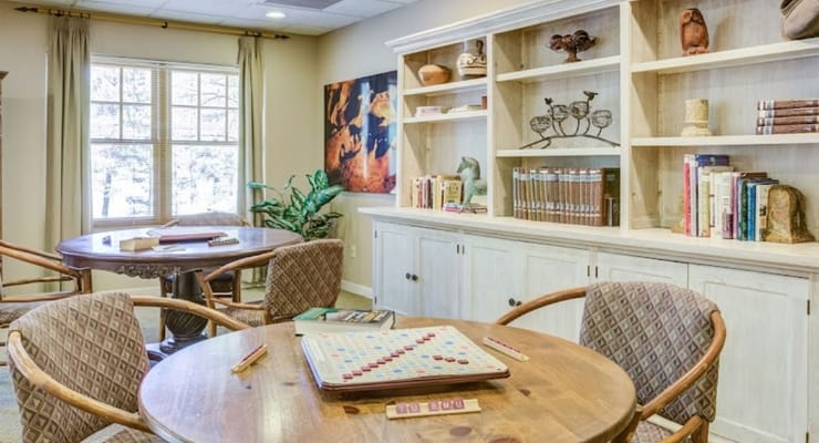 Cozy game room with wooden tables and bookshelves at The Peaks