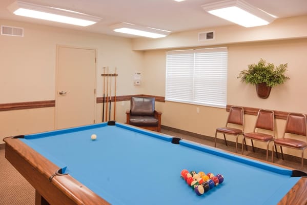 Billiards table in a recreational room with seating and large windows