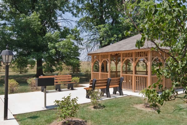 Wooden gazebo with benches surrounded by greenery