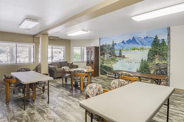 A bright common room with tables and a scenic mural.