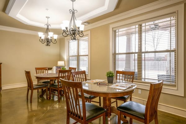 Cozy dining area featuring wooden tables and chairs, large windows, and a chandelier.