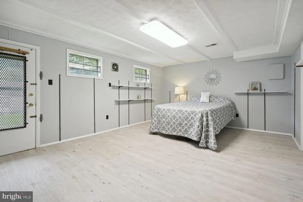 A cozy bedroom featuring a bed, lamp, and shelves.