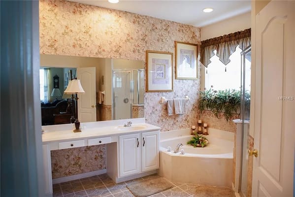 Well-lit bathroom with a tub, shower, and floral decor