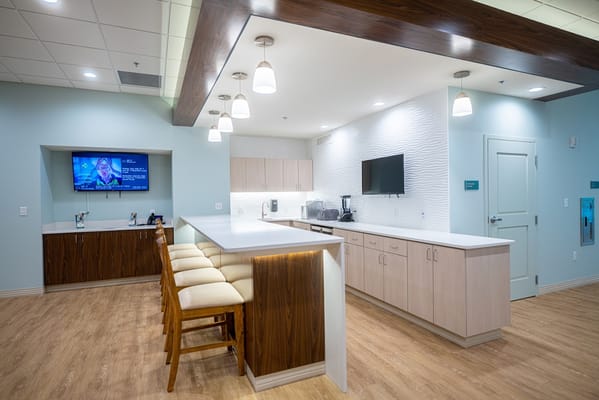 Clean and modern kitchen space with seating and TV.