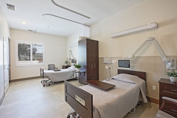 Clean and spacious patient room with two beds and modern amenities.