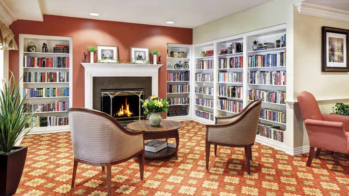 A cozy living room with bookshelves, a fireplace, and seating areas.